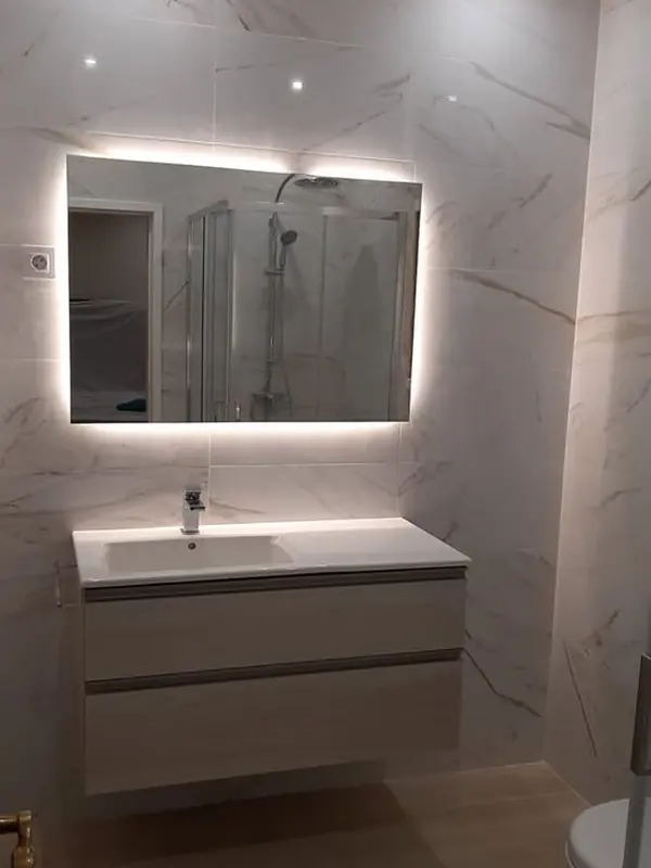 Casa de banho com revestimento tipo mármore, móvel suspenso e espelho com luz