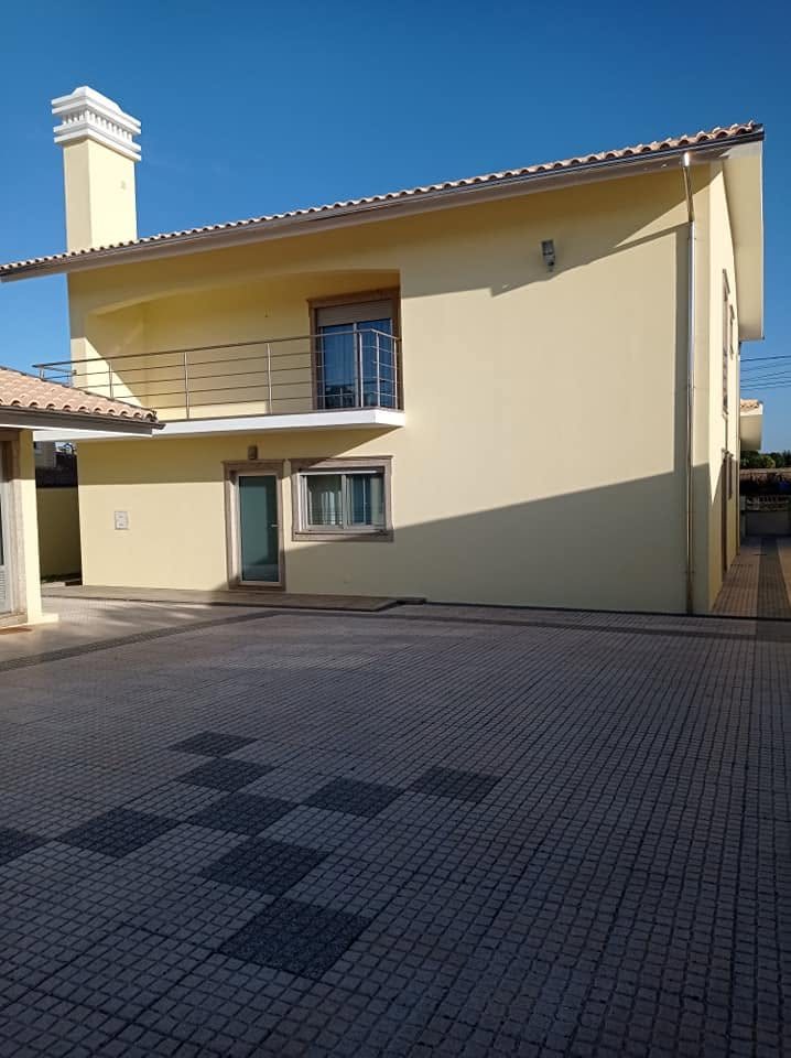 Moradia de dois pisos com a fachada pintada de amarelo claro depois da remodelação exterior