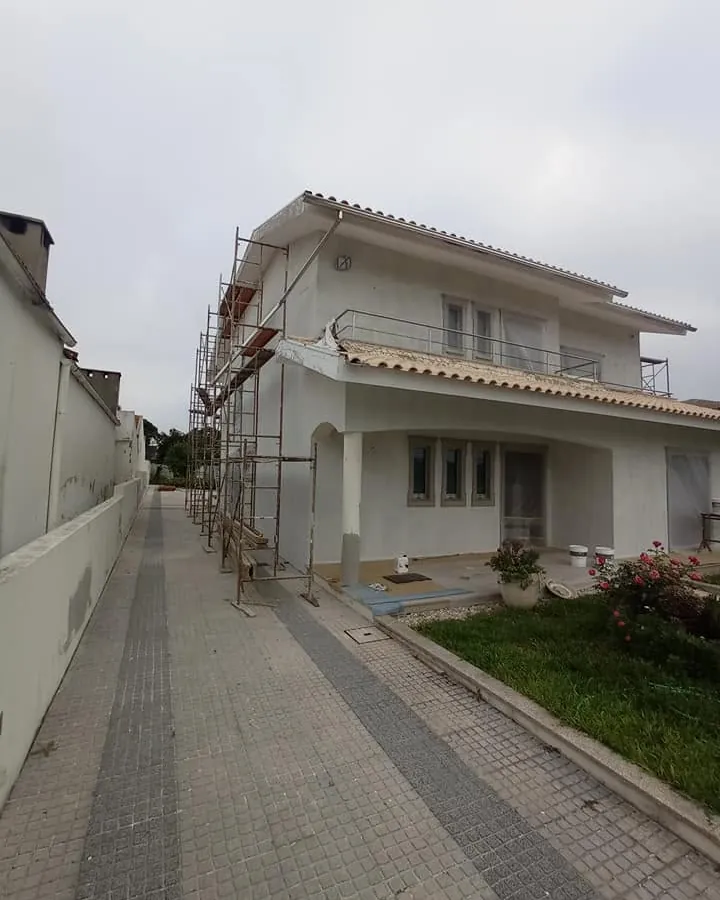 Moradia com andaimes e paredes brancas durante a obra