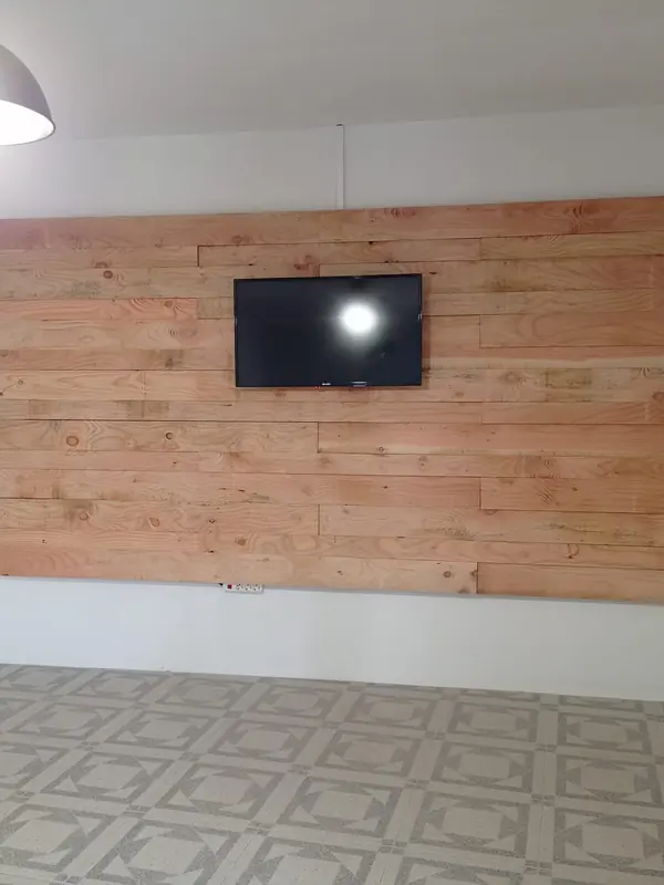 Sala com uma parede revestida a tábuas de madeira e televisão