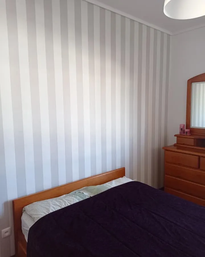 Quarto com a parede pintada às riscas cinzentas e brancas