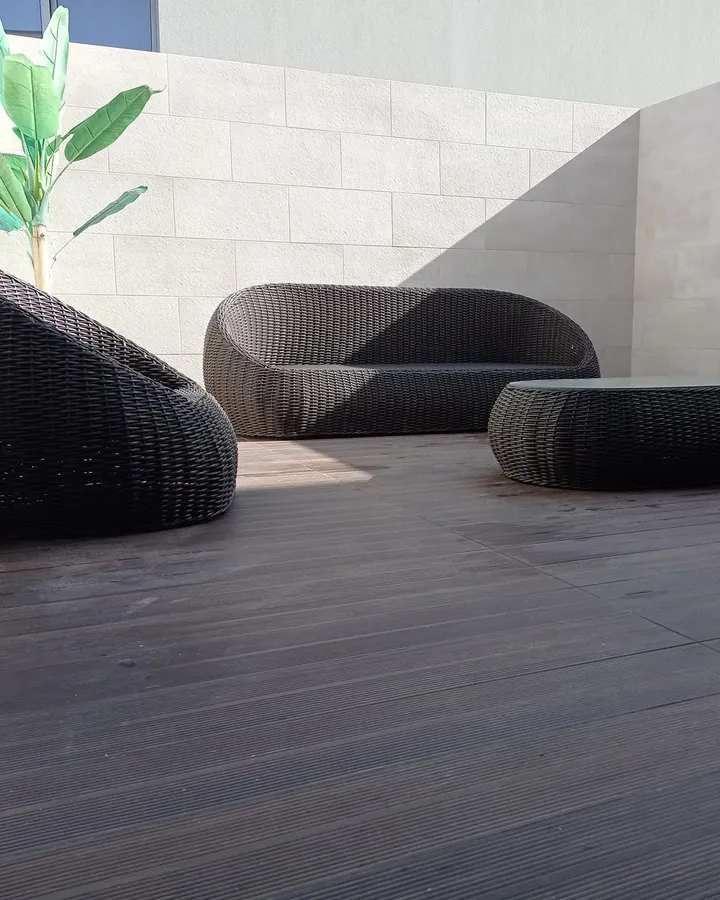Terraço acabado, com as paredes revestidas a pedra clara e mobiliário